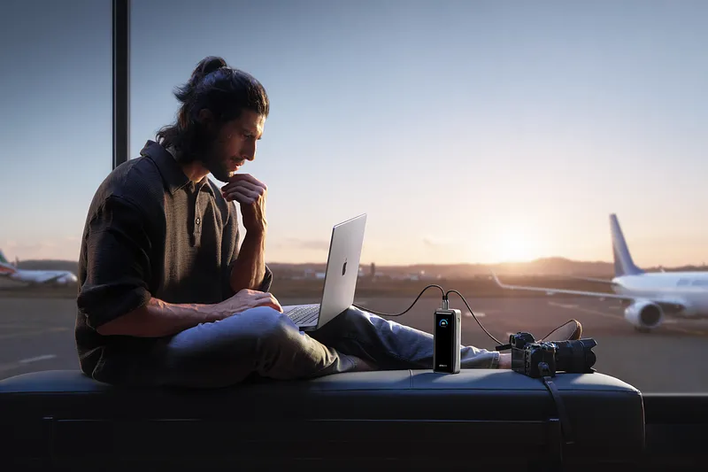 Persona utilizando un ordenador en el aeropuerto mientras carga la cámara